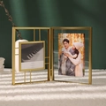 Modern gold metal folding photo frame with 4x4in square glass display on white fur carpet - Standard / Gold