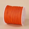 Roll of orange 0.8mm nylon cord for handmade jewelry weaving on white spool - Orange