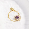 Detailed macro of gold chain ring featuring a purple stone and adjustable heart charm - Purple Zircon - Gold