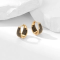 Detail of gold geometric hoop earrings with pavé black zircons on a white stone base - Black Zirconia