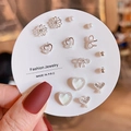 Close-up of titanium steel earring set with heart, flower, and bow designs on a display card - Silver Pink Rhinestone Flower (E0247-1)