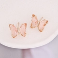 Macro view of butterfly earrings with peach zircon stones on a white ceramic plate - Peach
