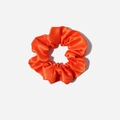 Detail view of glossy bright orange satin scrunchie with smooth silk texture and soft pleats - Orange