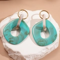 Detalle de pendientes geométricos de resina azul mármol con aros dorados sobre piedra - Pin de plata-Verde