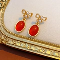 Dettaglio macro di orecchini vintage dorati con pietre rosse e fiocchi di perle - Un Paio di Orecchini (Perno in Argento-Oro-Rosso)