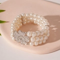 Dettaglio del bracciale di perle multistrato con fibbia a fiore di strass scintillanti - Braccialetto di Perle a Fiore
