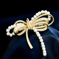 Elegante broche de lazo dorado con microcristales y perlas sobre seda azul oscuro - Dorado