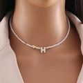 Collana di perle bianche con cuore dorato e pendente lettera H in conchiglia indossata - Lettera H