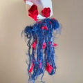 Dettaglio di orecchini a fiore rossi con lunghe nappe di filato blu scuro e aghi in S925 - Perno in Argento Sterling 925/Filato / Rosso/Blu