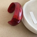 Detailopname van een brede open acryl armband met dieprode gemarmerde textuur - Rozerood