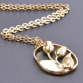 Elegant gold tulip pendant necklace with cutout design on a black matte background - Tulip Necklace / Gold