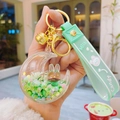 Detail of moon-shaped liquid keychain with green rabbit, silicone strap and bell - Green