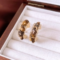 Nahaufnahme der goldenen Vintage-Creolen mit braunen Steinen auf weißem Samtbeutel - Gold Braun Falten (Silbernadel)