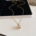 Detailansicht einer goldenen minimalistischen Kugelhalskette auf einer Schmuckschatulle - Gold