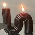 Black S-shaped wave textured scented candle with dual wicks lit on a reflective surface - Large S-Shape / 10x10x5cm Box / Black