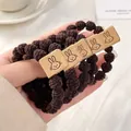 Set of four dark brown elastic hair ties with leather rabbit patches in hand - Knit With Rabbit Tag / Dark Coffee Rabbit