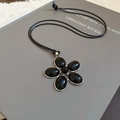 Detailopname van hars bloem hanger met zwarte bloemblaadjes en zilveren rand op een boek - Zilver-Zwart