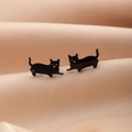Vista macro de pendientes de gato negro sobre fondo de seda beige suave - Estilo de Gato con Pata Extendida (790) / Negro