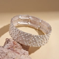 Detail view of silver wide cuff bracelet with rectangular links and grid texture on a stone - Silver