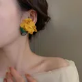Detail of a large yellow fabric flower earring with green leaves worn by a model - Yellow Fabric Flower (26#)