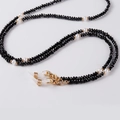 Detail of beaded glasses chain with black faceted beads, white pearls and gold accents - Black