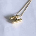 Macro shot of 3D polished gold letter H pendant on a delicate chain necklace - Letter H