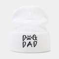 Close-up of white knitted beanie with black Dog Dad text and paw print embroidery - DOG DAD / White