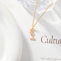 Detail of gold letter I pendant necklace with zircon stone on white background - Letter I