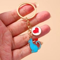 Cute metal cat and red heart pendant keychain with gold ring on a beige background - Blue
