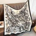 Detail showing elegant flower and bird prints on silk scarf draped over a leather sofa - 90*90cm / Off White