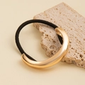 Macro view of gold C-shaped metal ornament on black elastic hair tie with stone texture - Wide Crescent Metal Hair Tie / Gold