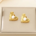Detailaufnahme von herzförmigen Perlenohrringen auf einem champagnerfarbenen Etui - Gold Hohles Herz Perle (24x20mm)