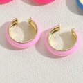 Dettaglio ravvicinato degli orecchini a cerchio a C in smalto rosa e oro su fondo bianco - Rosa