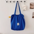 Detailed view of blue pleated tote bag featuring drawstring closure and brand label - Blue