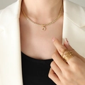 Golden necklace with letter D zircon pendant and stackable rings on a female model - Letter D / Gold
