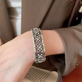 Nahaufnahme eines Vintage-Armbands mit hohlen Blumen und Strasssteinen am Handgelenk - 16# Silbernadel - Silber