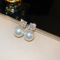 Macro detail of elegant gold-plated stud earrings with square zircon and white pearl - Square Zirconia Pearl Drop