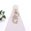 Golden metal letter G keychain with crystal crown and lobster clasp on a white stand - Letter G / Gold