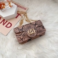 Brown snakeskin crossbody bag with dual gold rings and chain strap on plush background - Pink