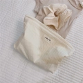 Dettaglio macro della pochette trapuntata in cotone a righe con etichetta in tessuto - Bianco Sporco