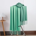 Close-up of green cashmere scarf with tassel fringe and textile material label - No.22 Bean Green