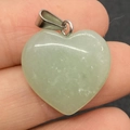 Light green heart-shaped natural stone pendant with a silver metal clasp shown on hand - 20mm / Green Aventurine