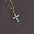 Detail of gold cross pendant necklace featuring six light blue rhinestones on stone background - Lake Blue Cross Shape