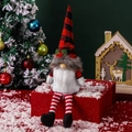 Kerstkabouter met lange benen en rood geruite hoed zittend op een geschenkdoos - Kerstmuts Stijl