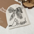 Cream knit beanie featuring a black hand-drawn bow and Blessed lettering print - White