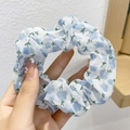Detail of blue and white chiffon scrunchie with cloud pattern held in hand against a wall - Blue Small Floral