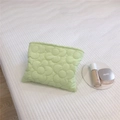 Detailed close-up of mint green quilted floral down pouch on textured white fabric - Light Green