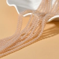 Macro detail of 4mm faceted champagne rondelle beads on white ceramic tray - Opal Nude Pink