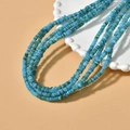 Close-up of multi-strand blue beaded necklace on a white scalloped plate with orange background - 6# Lake Blue 4mm (1 Strand)