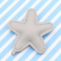 Grey leather star keychain with white stitching detail and hanging loop on striped background - Gray
